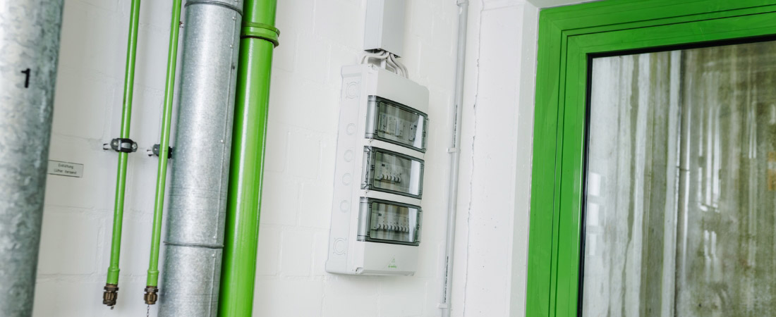 Bild der AK 36 Kleinverteiler von Spelsberg, montiert zwischen grünem Türrahmen und Rohren