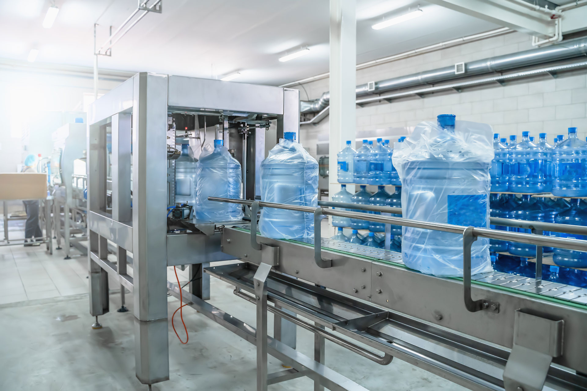 Getränkeherstellung in Lebensmittelindustriehalle, blaue Wasserflaschen auf Förderband