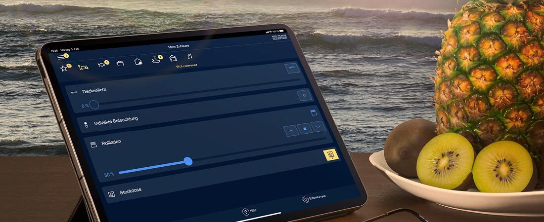 JUNG HOME auf dem Tablet mit Urlaubssituation im HIntergrund