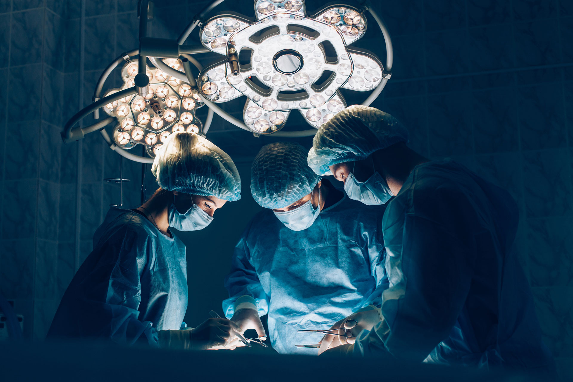 Ärzte operieren auf dem OP-Tisch mit einer OP-Beleuchtung im Hintergrund