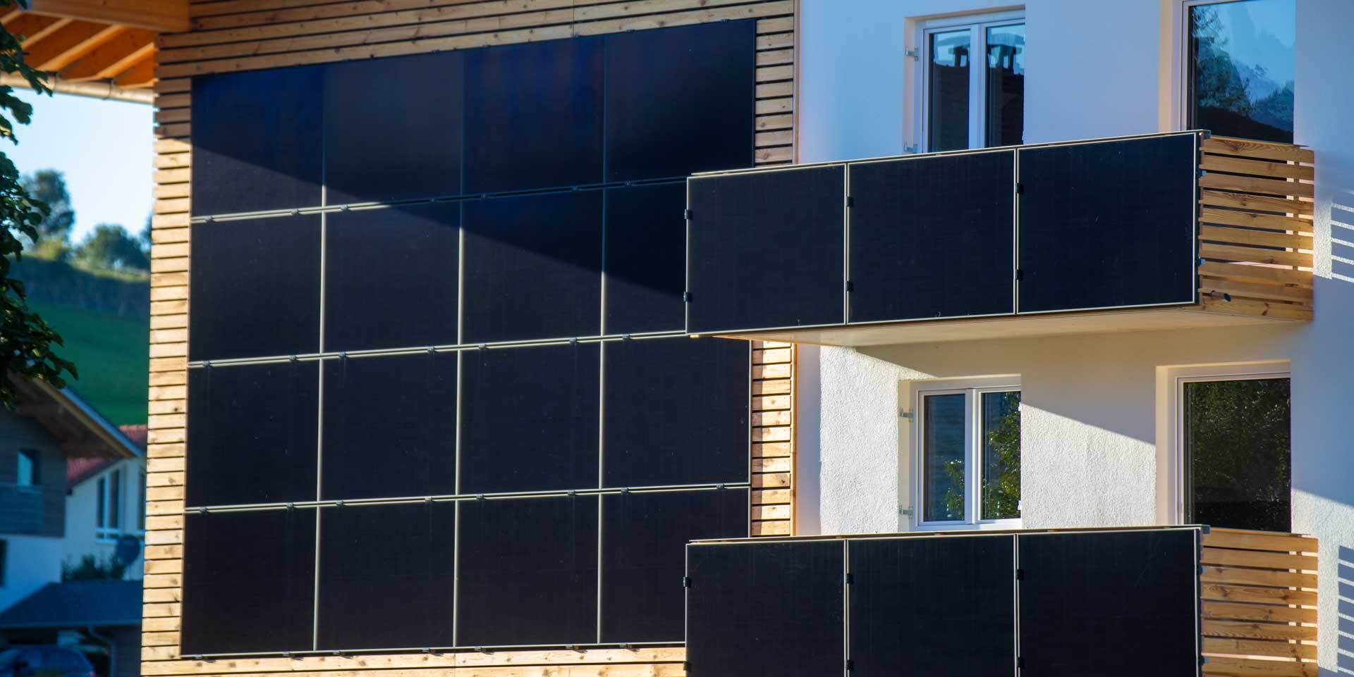 Haus mit Solarpanelen an der Hauswand und einem Balkonkraftwerk an den beiden Balkonen